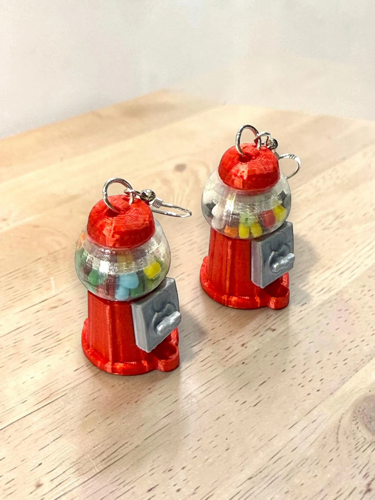 Close-up view of red gumball machine earrings