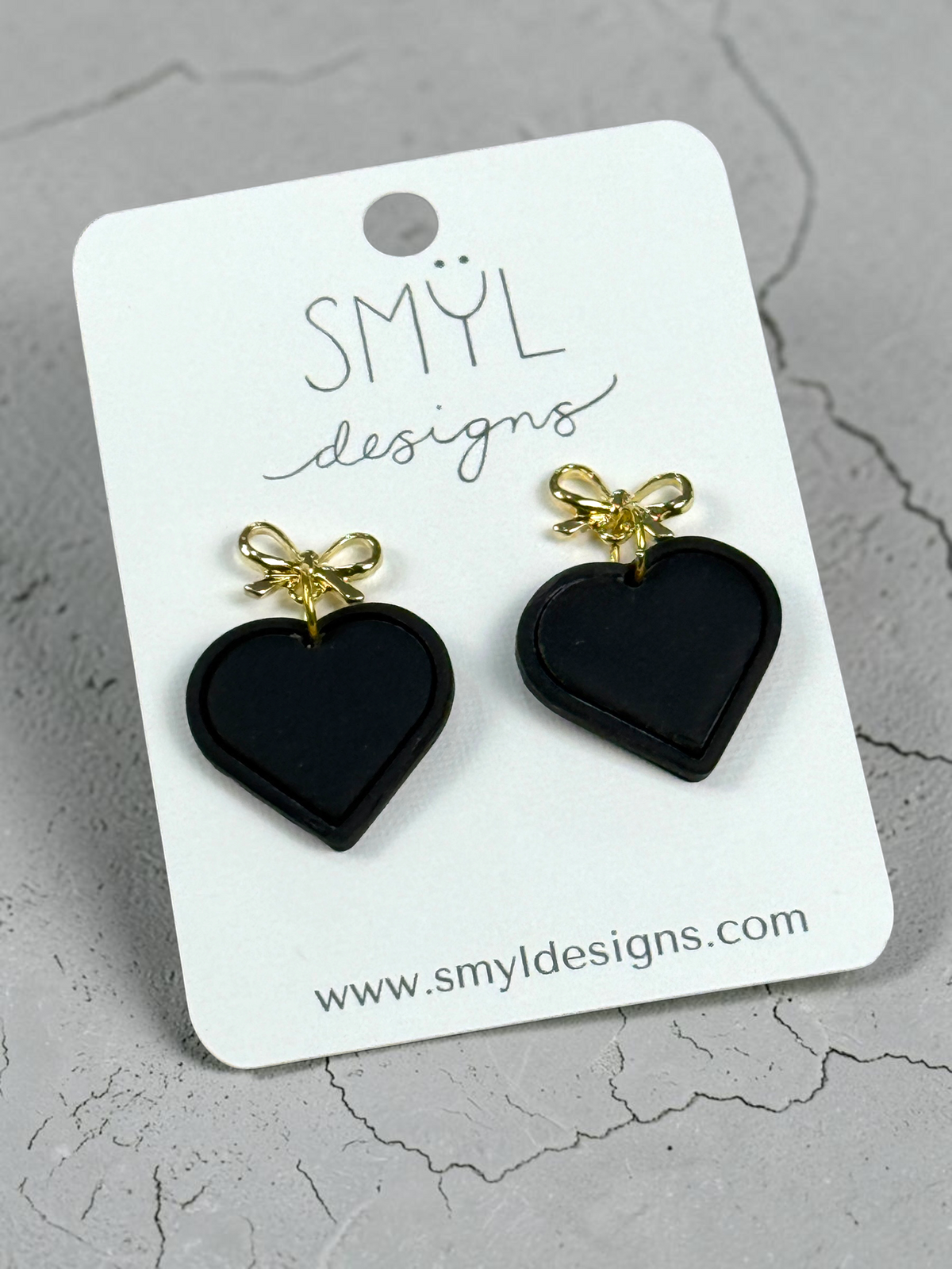 Black single-heart dangle earrings with gold bow studs