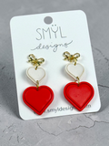 Angled view of red graduated double-heart dangles with gold bow studs