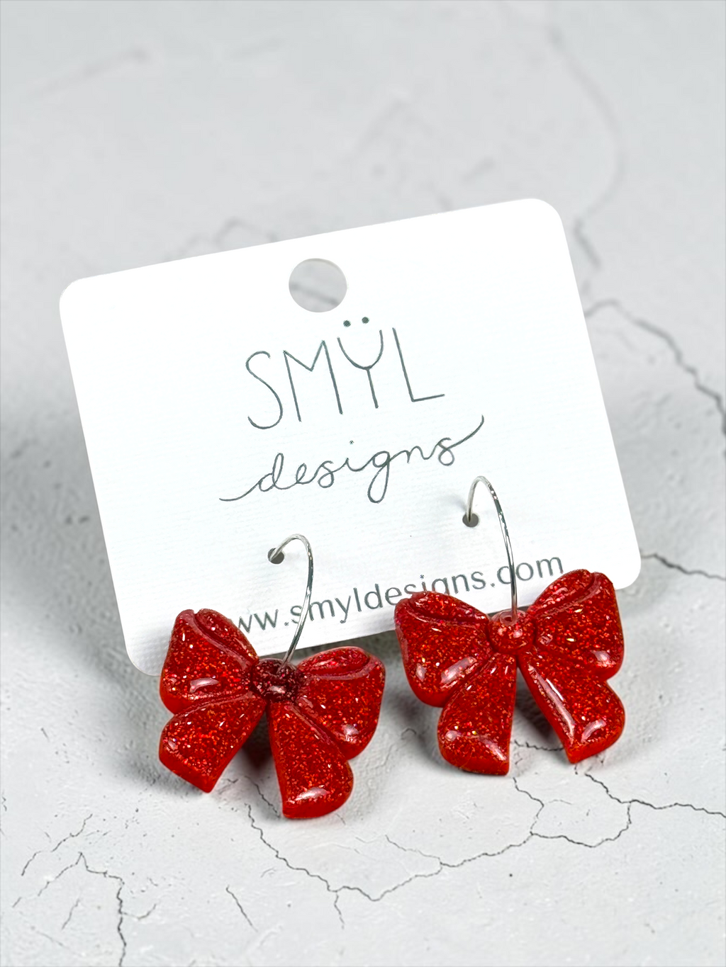 Angled view of red glitter large-bow hoop earrings